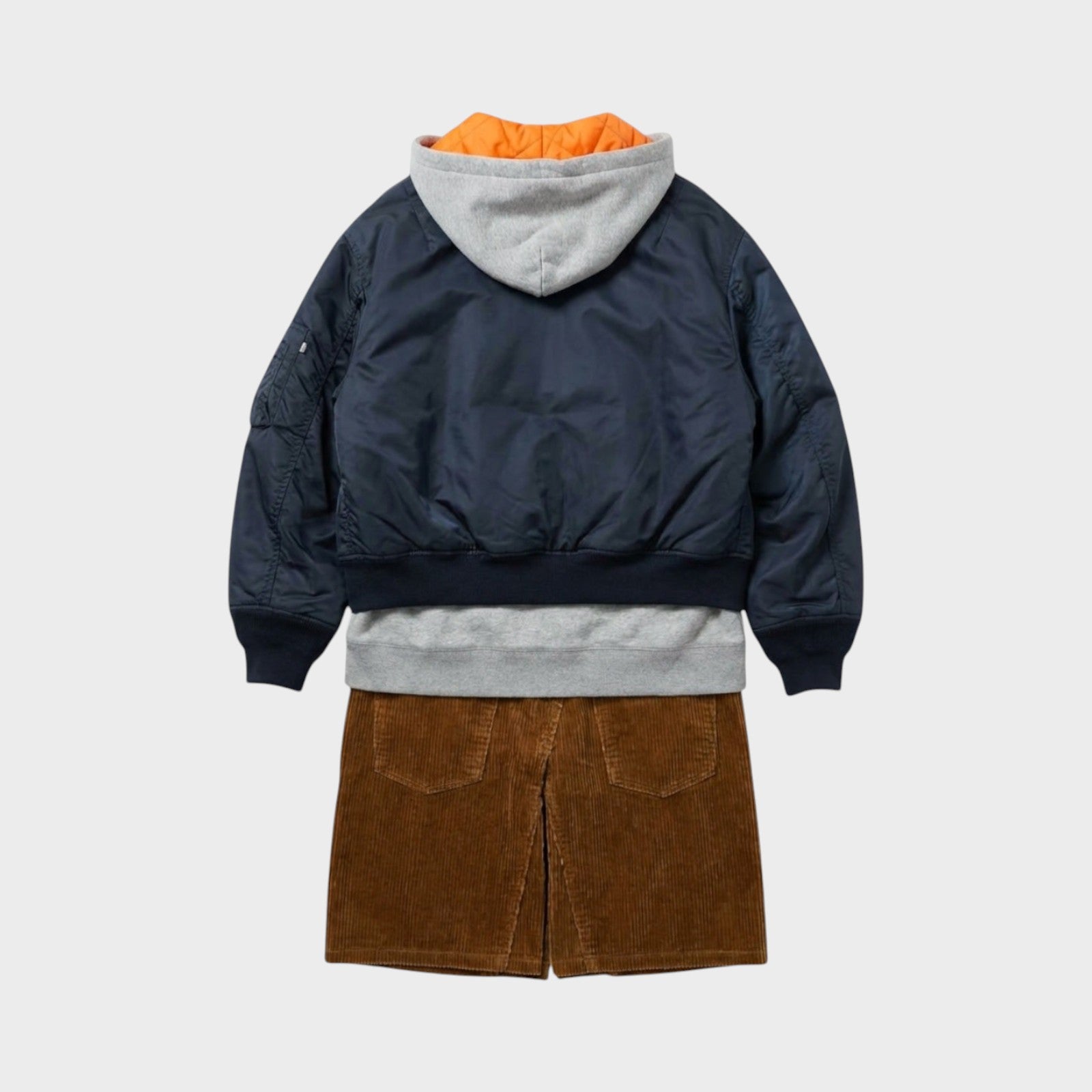 Tasoni navy blue bomber jacket layered over a grey hoodie and brown corduroy skirt. Orange lining visible.