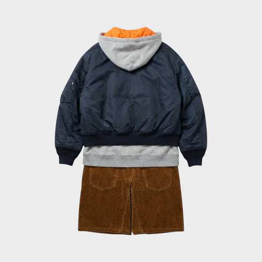 Tasoni navy blue bomber jacket layered over a grey hoodie and brown corduroy skirt. Orange lining visible.