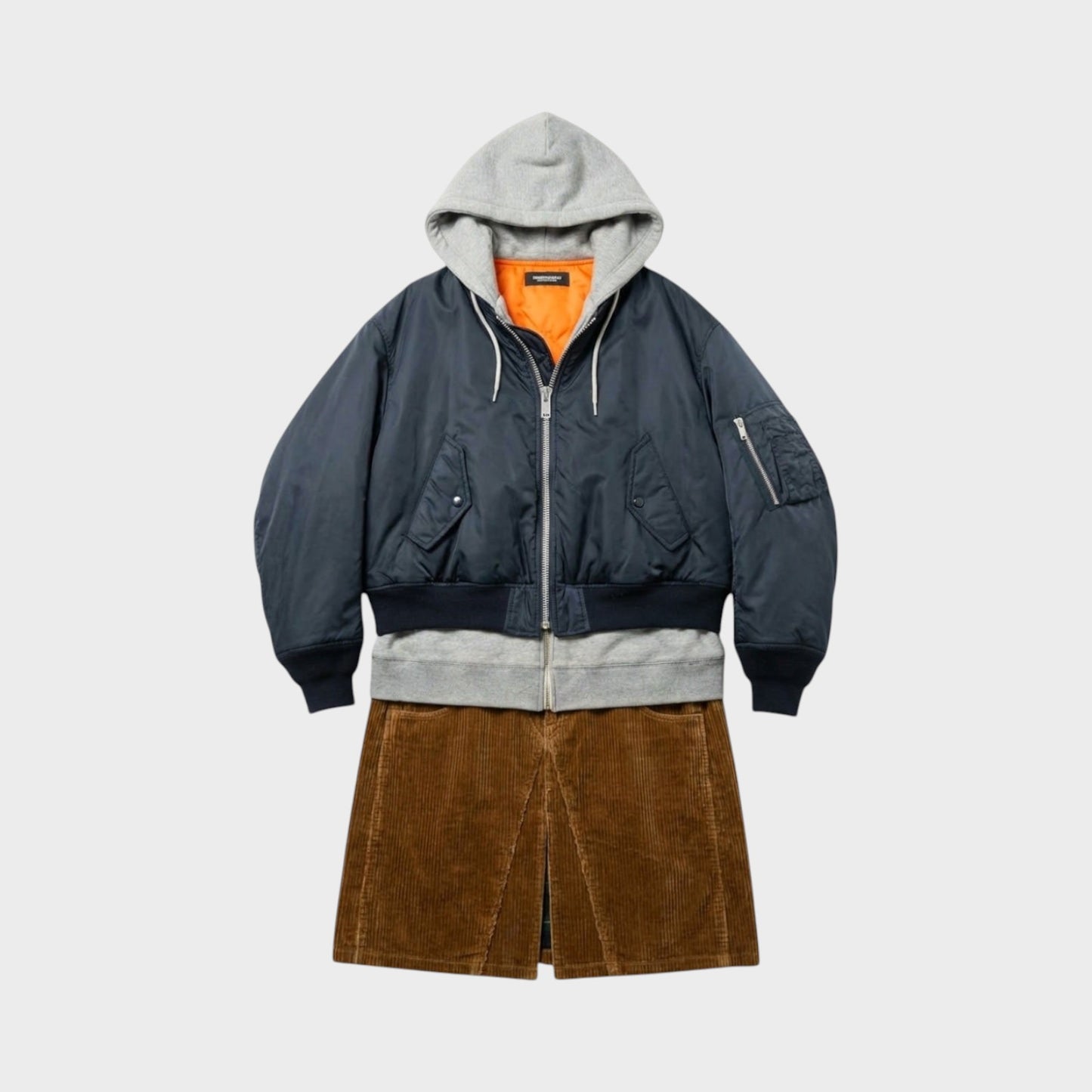 Tasoni navy blue bomber jacket with grey hood and orange lining, layered over a grey sweatshirt and brown corduroy skirt.