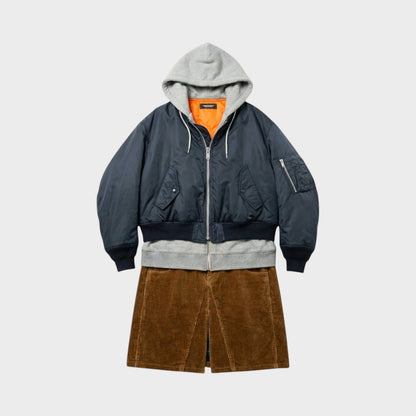 Tasoni navy blue bomber jacket with grey hood and orange lining, layered over a grey sweatshirt and brown corduroy skirt.