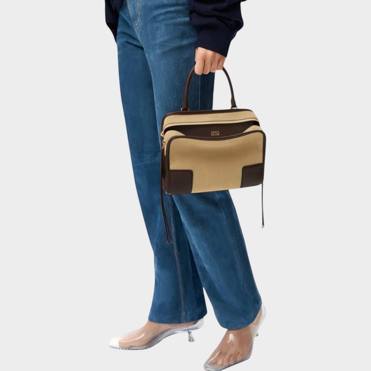 Tasoni Loewe Amazona 180 small beige and brown suede bag held by a model wearing blue jeans and clear heels.