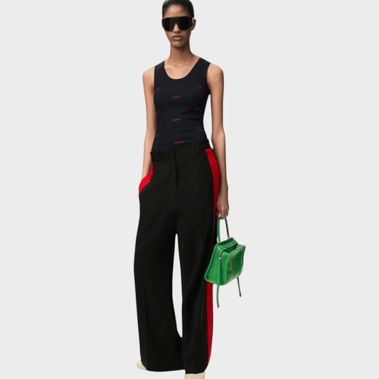 Model wearing a black Tasoni Loewe cotton tank top with red logo print, paired with black trousers and green bag.