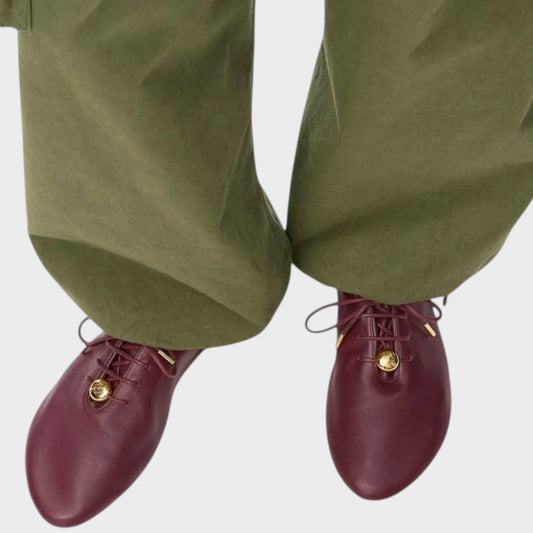 Tasoni Loewe Pebble soft burgundy leather lace-up ballerina flats with gold hardware worn with olive green trousers.