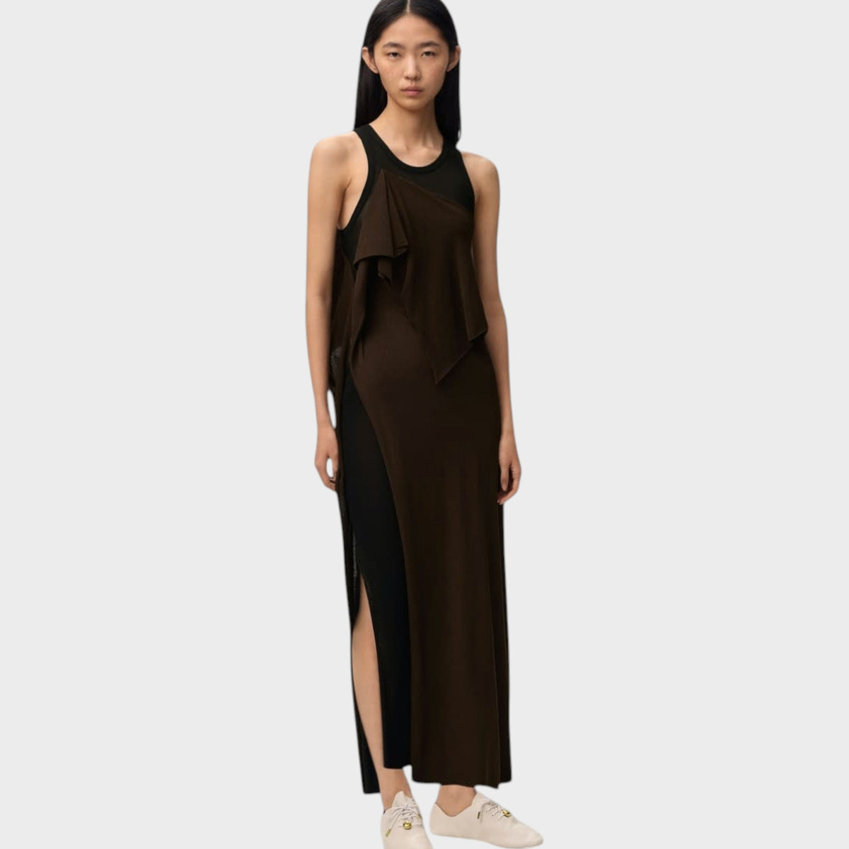 Model wearing a Tasoni Loewe long dress in dark brown and black with mesh panels and a side slit on a grey background