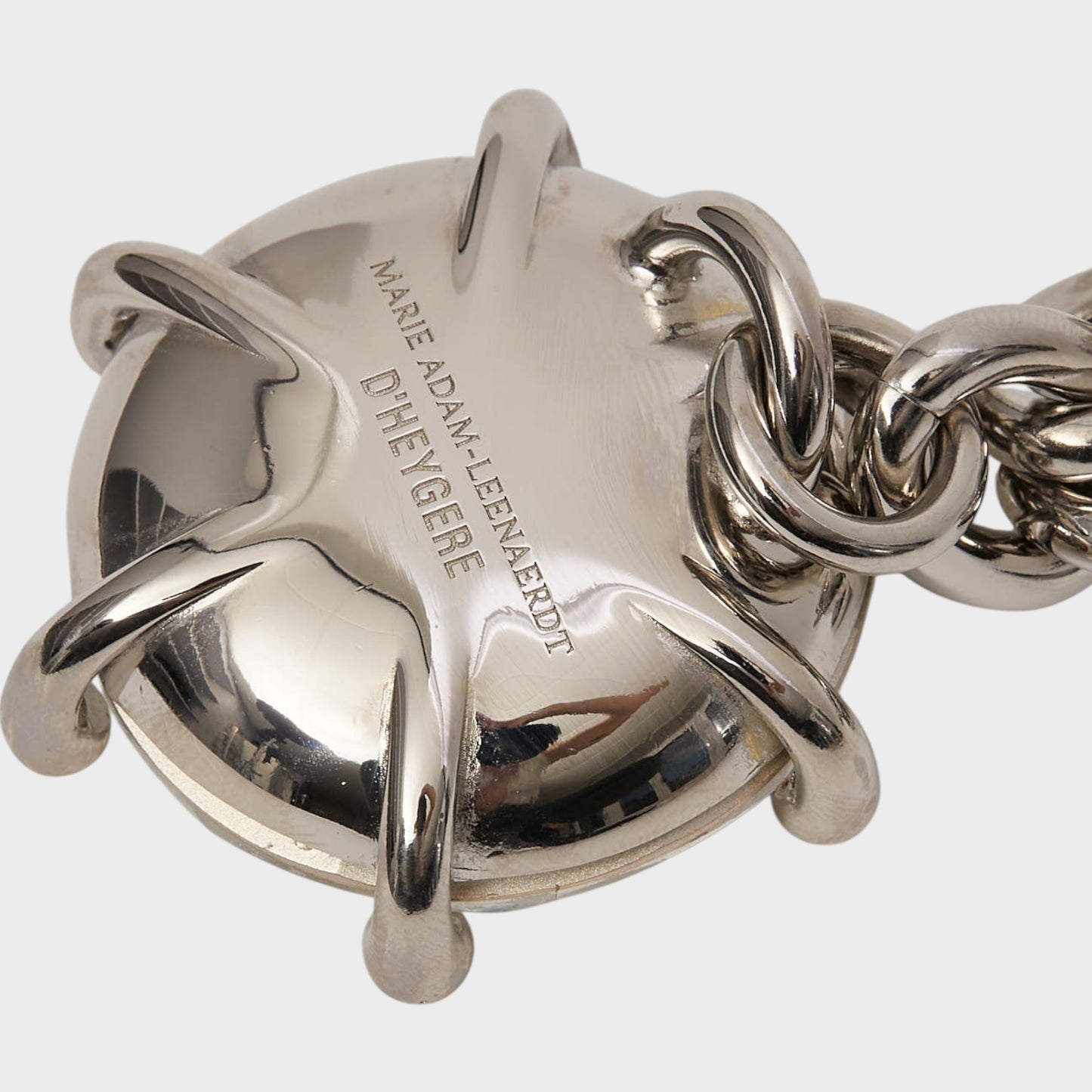 Tasoni Marie Adam-Leenaerdt brass necklace with a large, circular, silver-tone pendant and a chunky chain. Engraved text visible.
