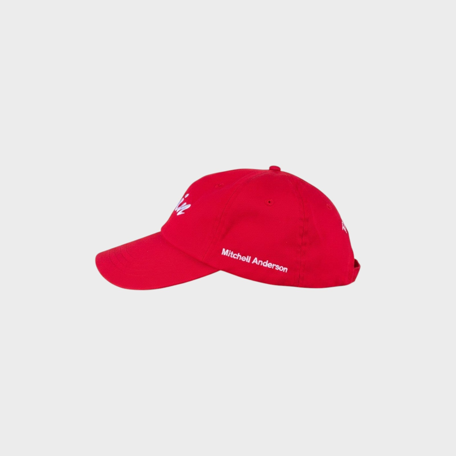 Tasoni x Mitchell Anderson red baseball cap with white embroidered logo on front and text on side.