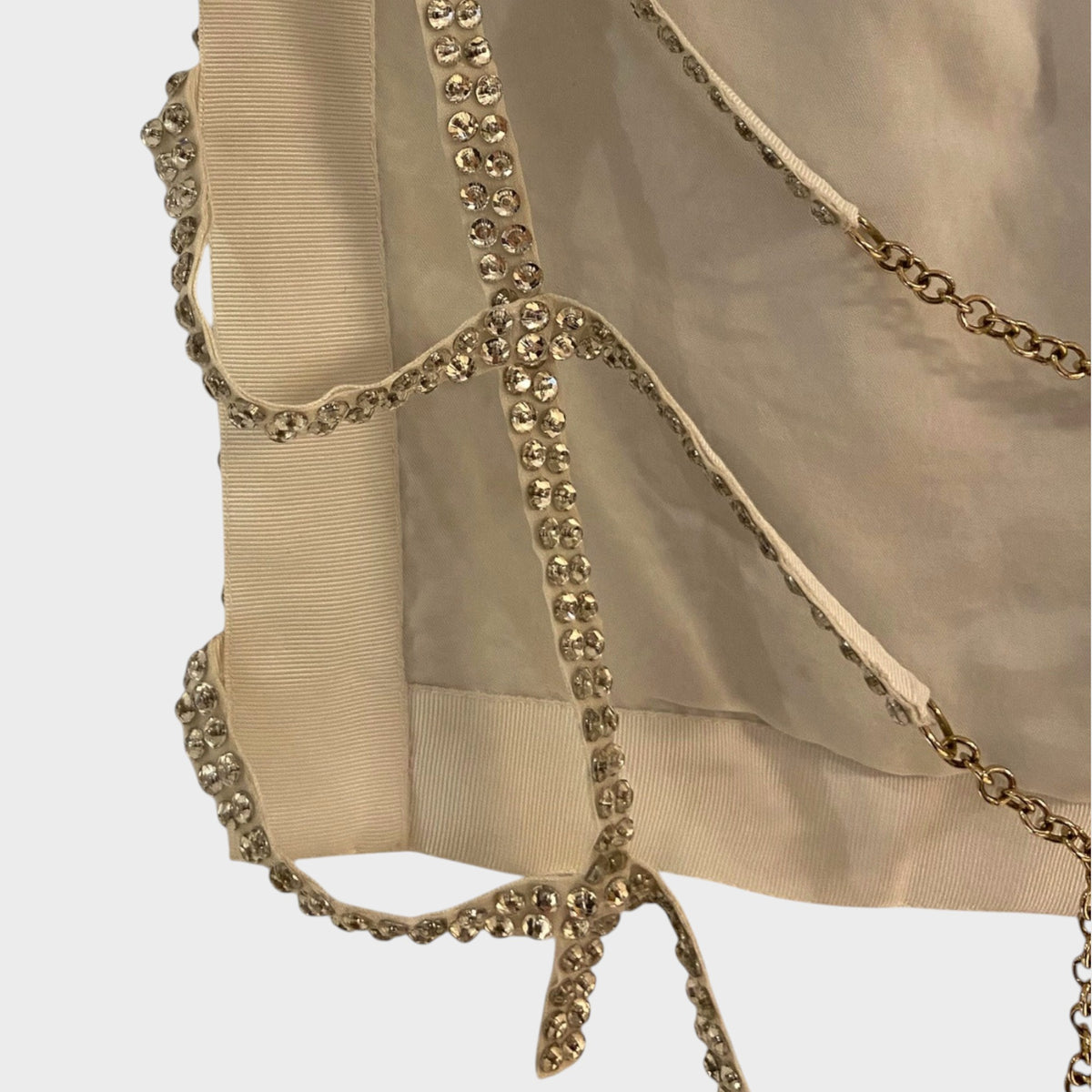 Tasoni Nina Ricci beige sheer top featuring intricate crystal-embellished trim and delicate gold chain detailing.