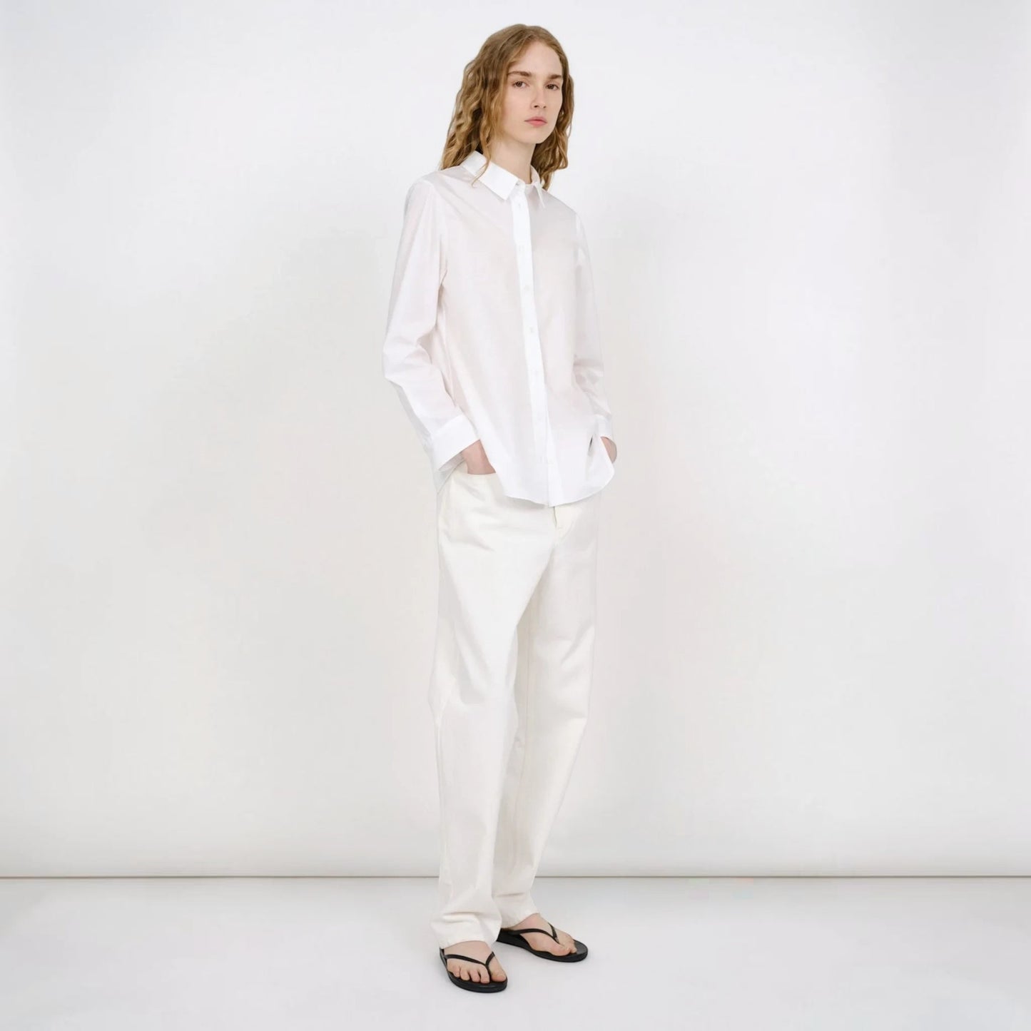 Model wearing a white Tasoni Partow Bryant cotton poplin shirt with a classic collar and long sleeves.