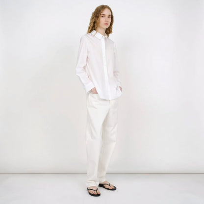 Model wearing a white Tasoni Partow Bryant cotton poplin shirt with a classic collar and long sleeves.