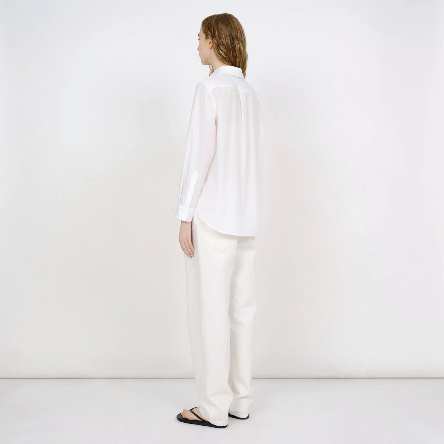 Model wearing a white Tasoni Partow Bryant cotton poplin shirt with a classic collar and long sleeves.