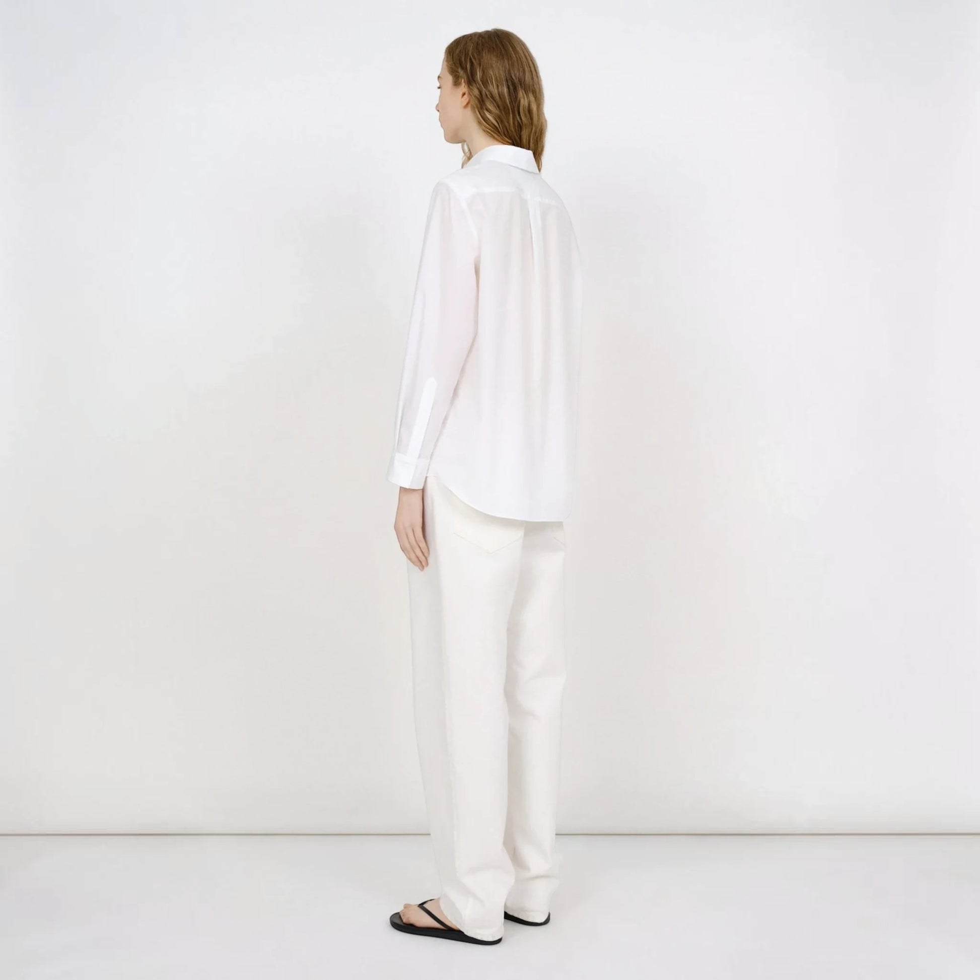 Model wearing a white Tasoni Partow Bryant cotton poplin shirt with a classic collar and long sleeves.