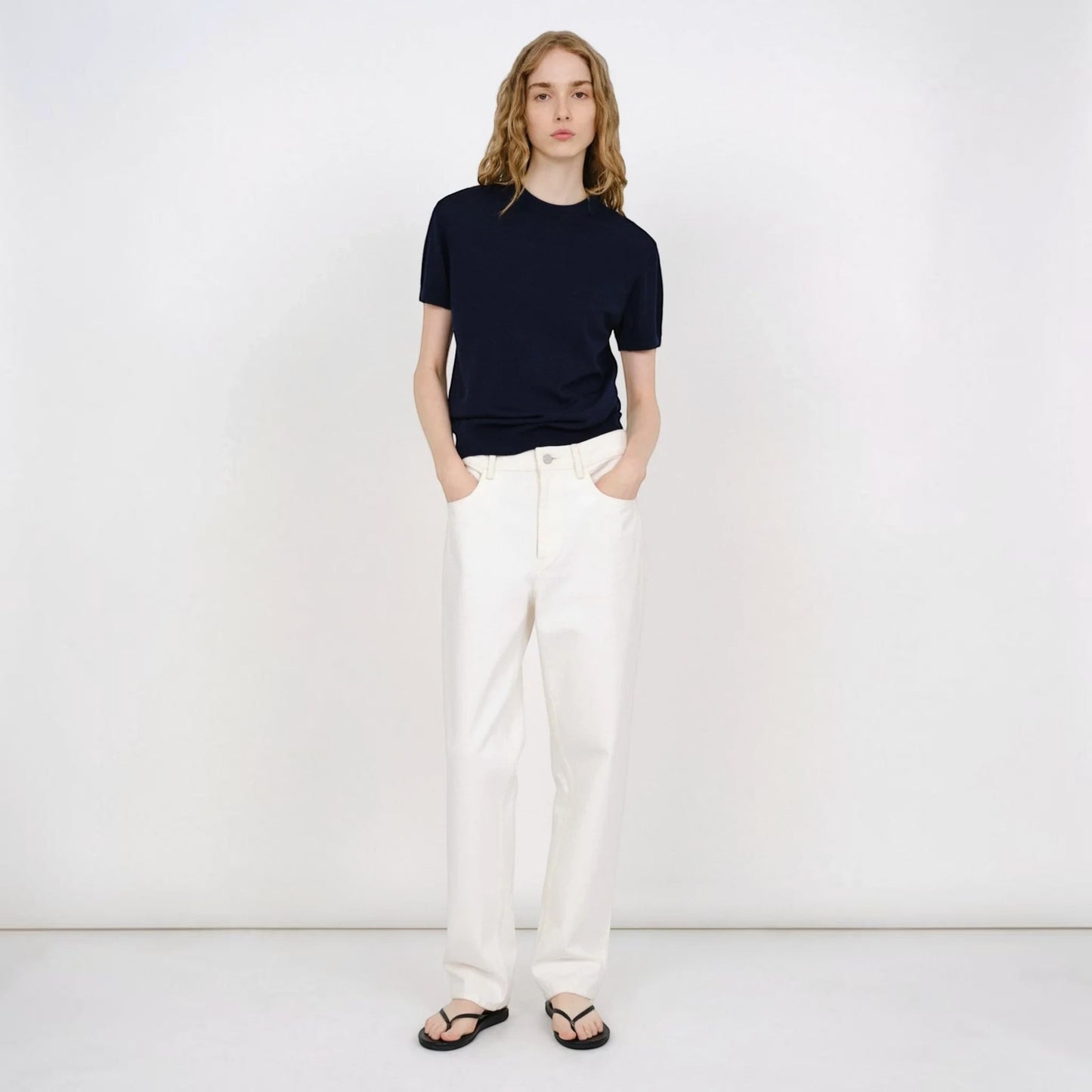 Model wearing a navy blue Partow Enzo wool sweater with short sleeves and white trousers from Tasoni.