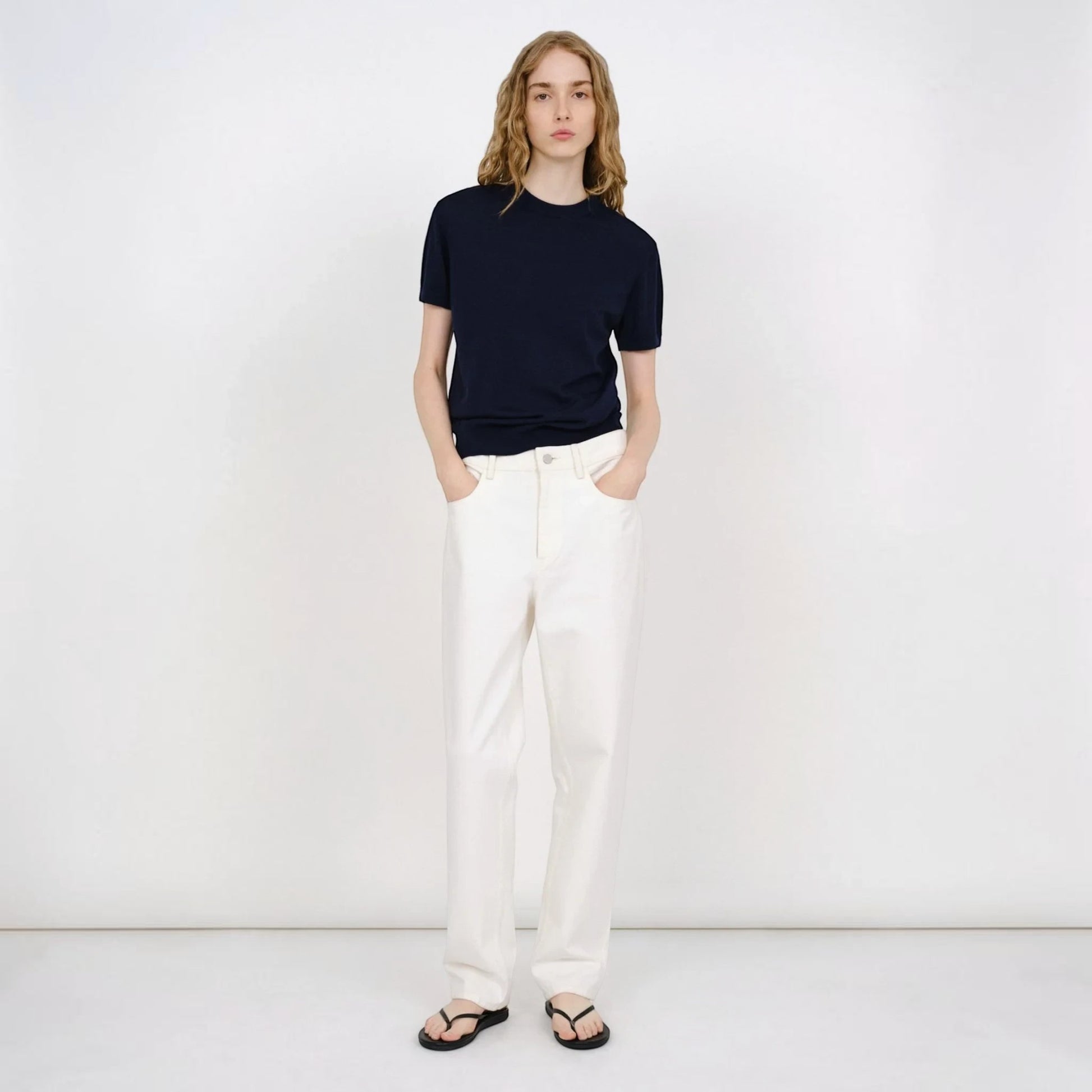Model wearing a navy blue Partow Enzo wool sweater with short sleeves and white trousers from Tasoni.