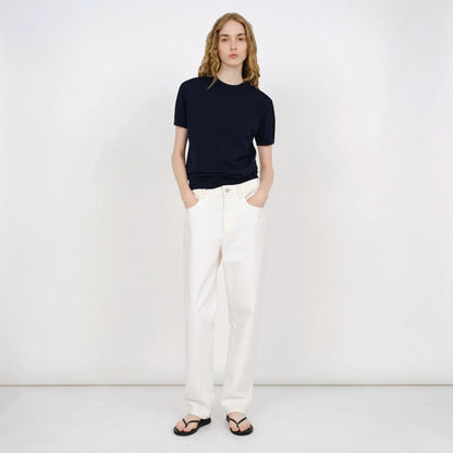Model wearing a navy blue Partow Enzo wool sweater with short sleeves and white trousers from Tasoni.