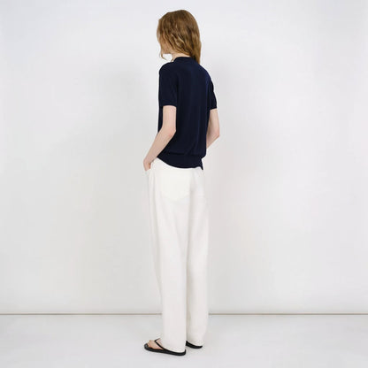 Model wearing a navy blue Partow Enzo wool sweater with short sleeves and white trousers from Tasoni