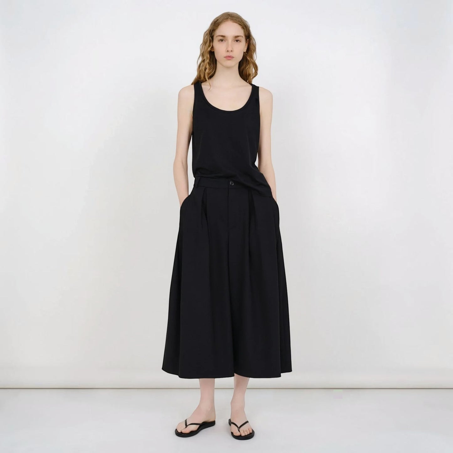Model wearing Tasoni Partow Ida black virgin wool wide-leg trousers with a high-waisted pleated design.