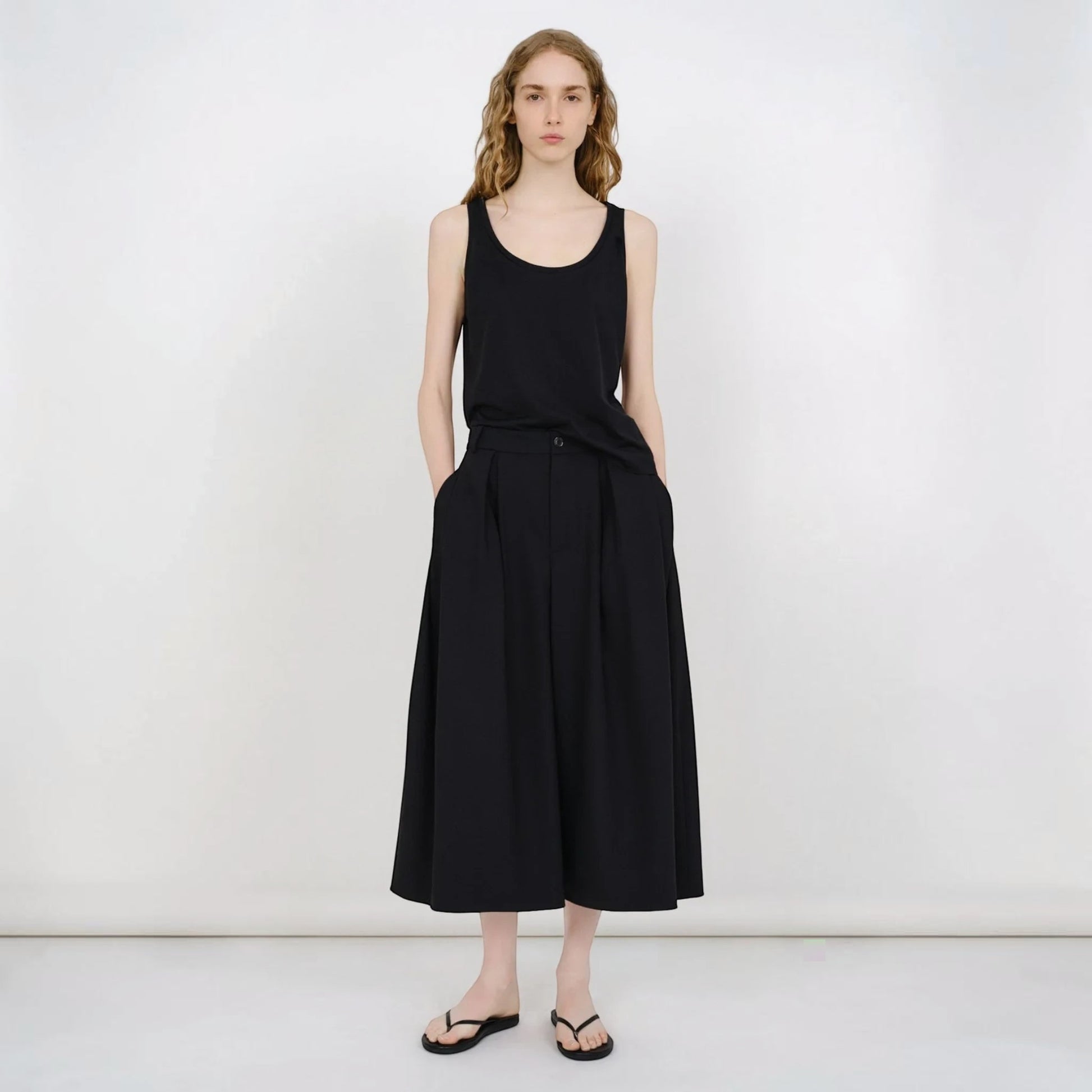Model wearing Tasoni Partow Ida black virgin wool wide-leg trousers with a high-waisted pleated design.