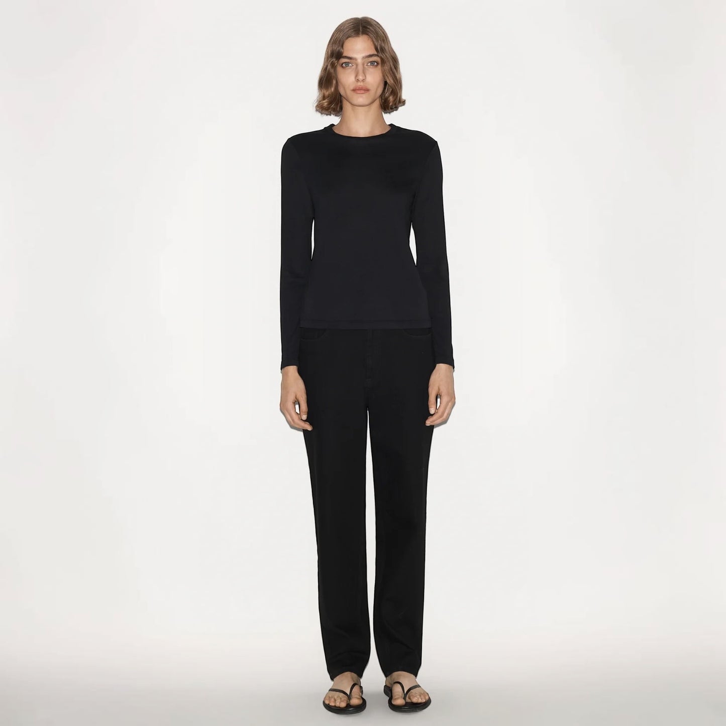 Model wearing a black Partow Marden long sleeve top with a crew neck, paired with black trousers by Tasoni.