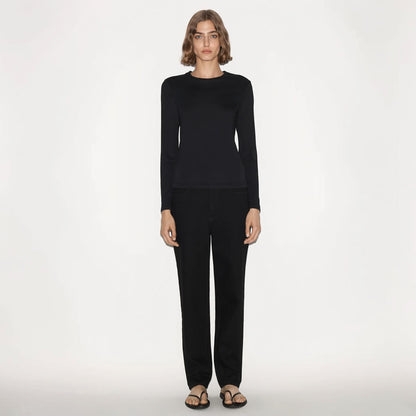 Model wearing a black Partow Marden long sleeve top with a crew neck, paired with black trousers by Tasoni.