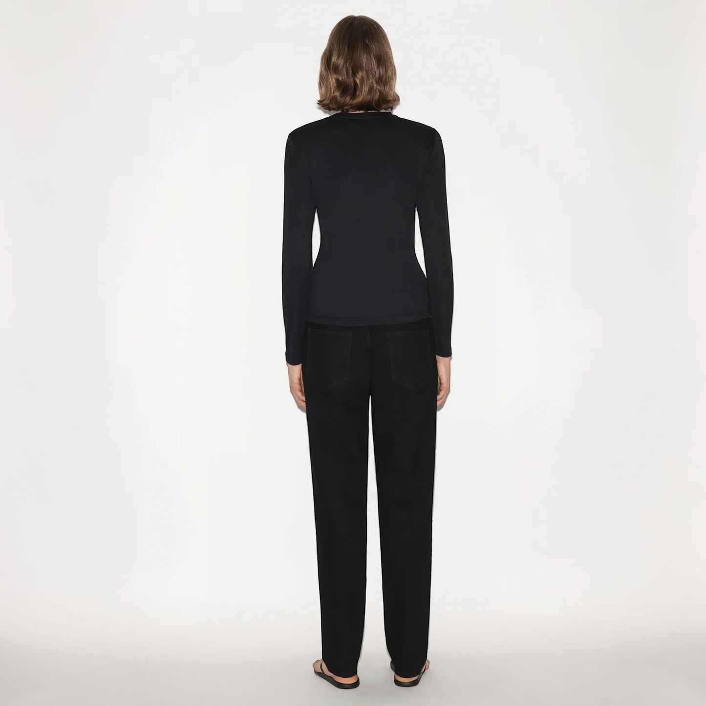 Model wearing a black Partow Marden long sleeve top with a fitted silhouette, paired with black trousers from Tasoni.