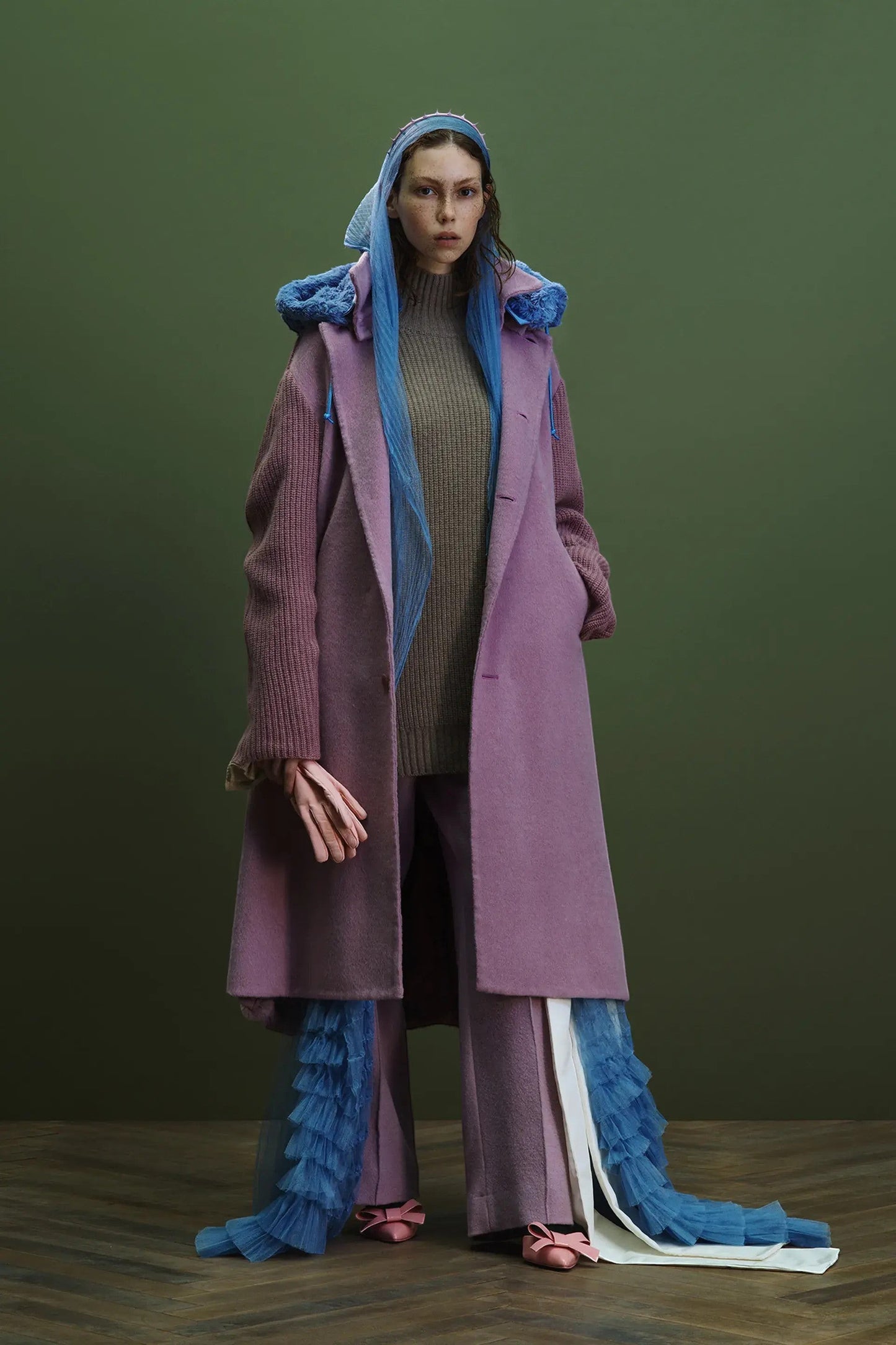 Tasoni dark pink cashmere blend coat with contrasting lilac knit sleeves and blue tulle trim. Model wears a grey sweater and matching trousers.