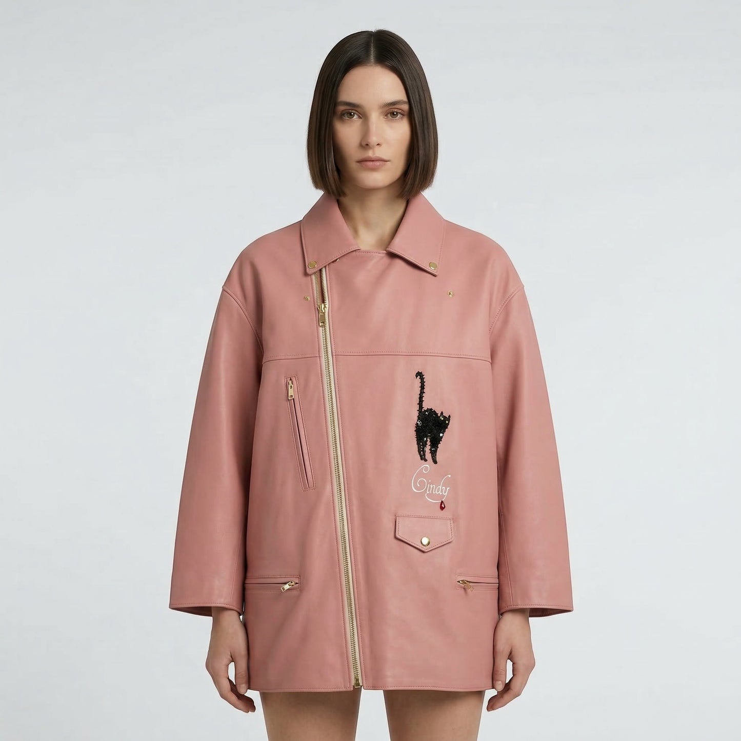 Tasoni pink leather biker coat with black cat appliqué and yellow lining. Features gold zippers and a unique asymmetrical closure.