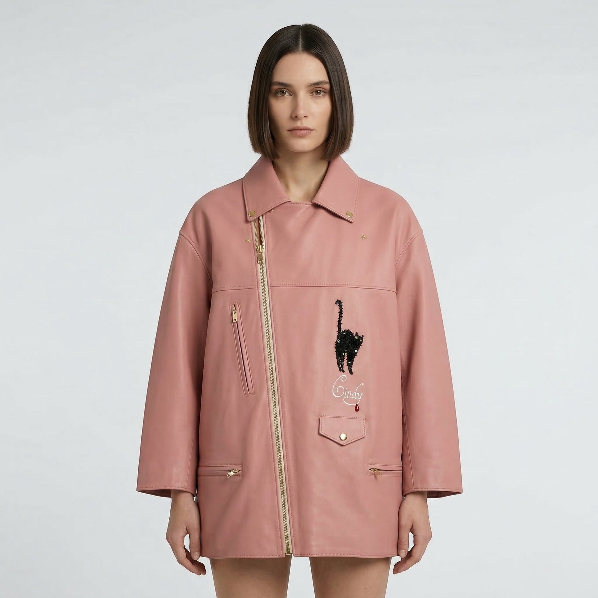 Tasoni pink leather biker coat with black cat appliqué and yellow lining. Features gold zippers and a unique asymmetrical closure.