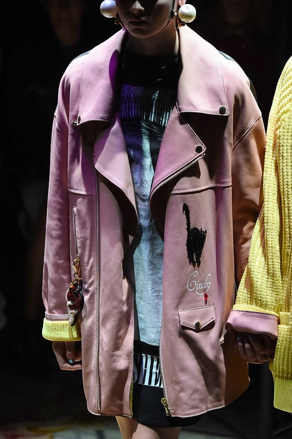 Tasoni pink leather biker jacket with black cat appliqué and yellow lining. Features zip closure, pockets, and a keychain.