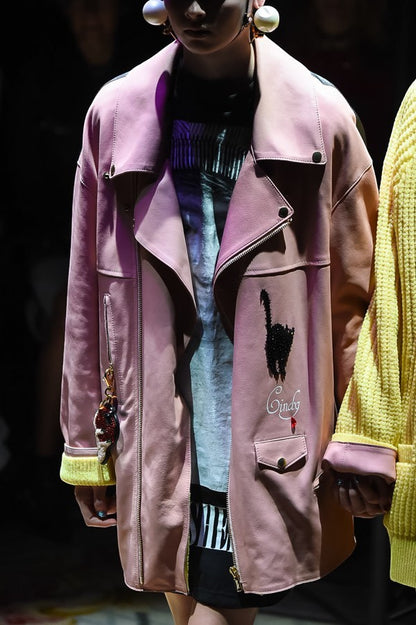 Tasoni pink leather biker jacket with black cat appliqué and yellow lining. Features zip closure, pockets, and a keychain.