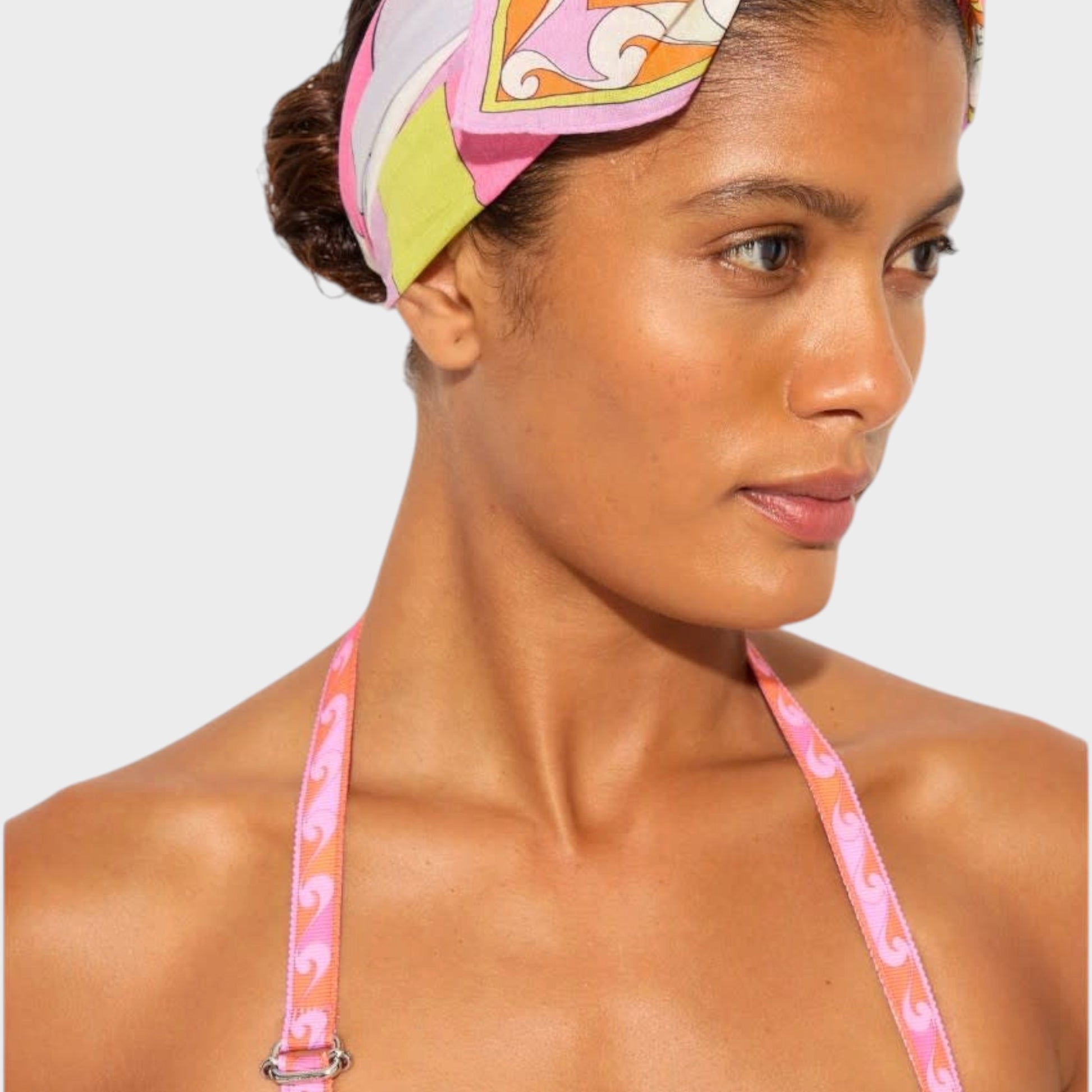 Model wearing a Tasoni Pucci bow headband bandana with a vibrant pink, orange, and white geometric print.