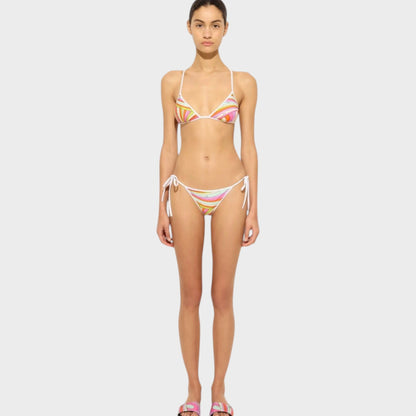 Model wearing a Tasoni Pucci triangle bikini top with a colorful abstract print and white tie-side bikini bottoms.