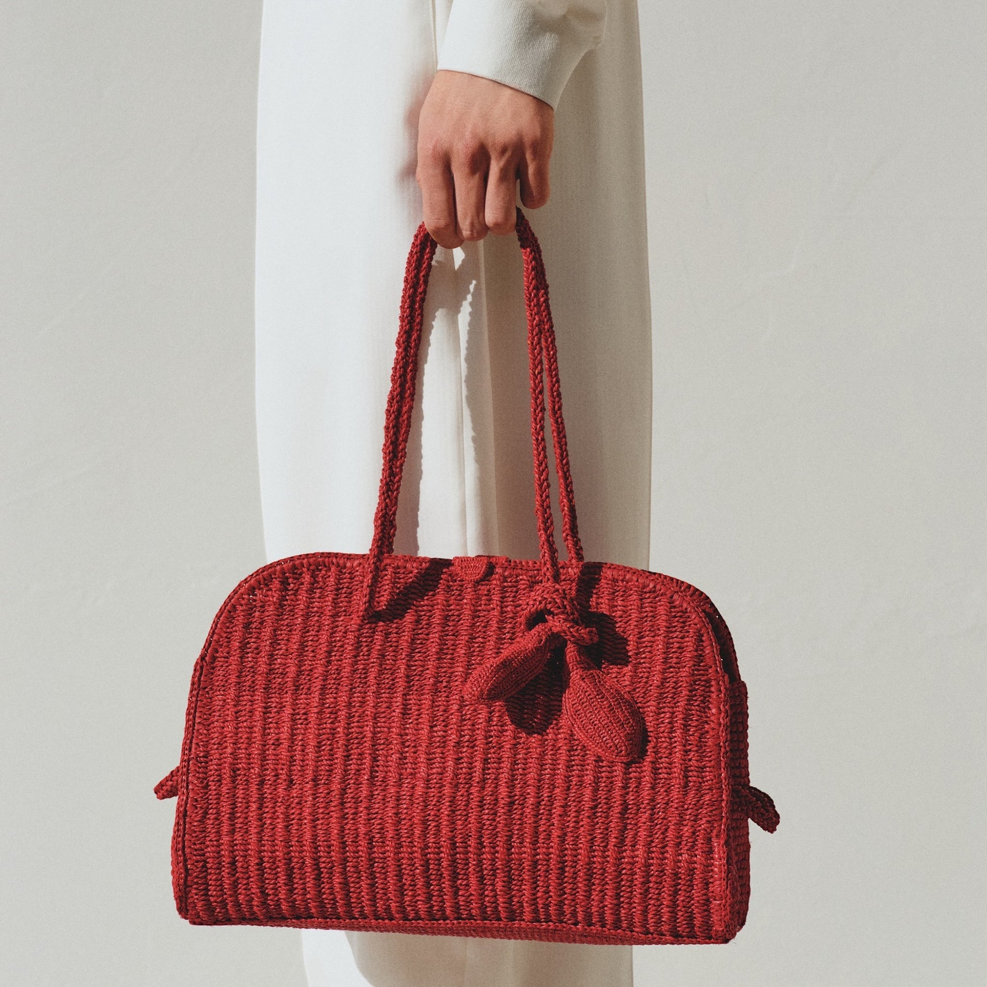 Tasoni red raffia tote bag with braided handles and a knotted detail on the front.