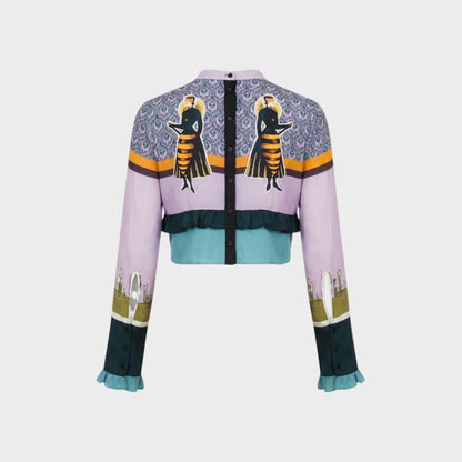 Tasoni Undercover Silk Top, a cropped jacket with a lilac base, featuring a patterned yoke with two figures, ruffled teal hem, and printed sleeves.