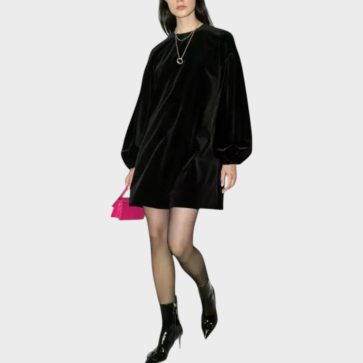 Model wearing a black Valentino velvet balloon mini dress with long sleeves, paired with black boots and a pink bag.