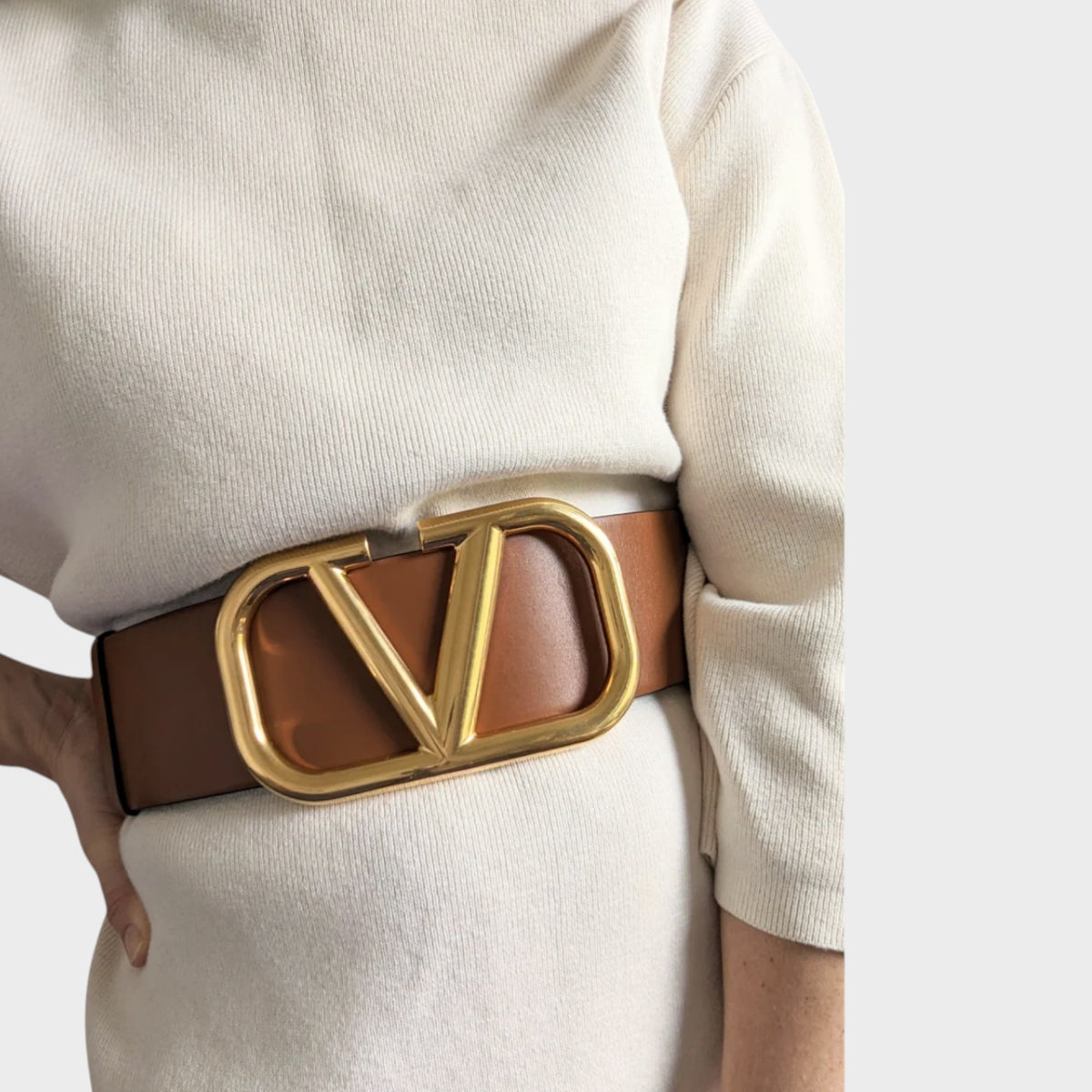 Tasoni Valentino V Logo belt in brown leather with a large gold-tone metal buckle worn over a white knit dress