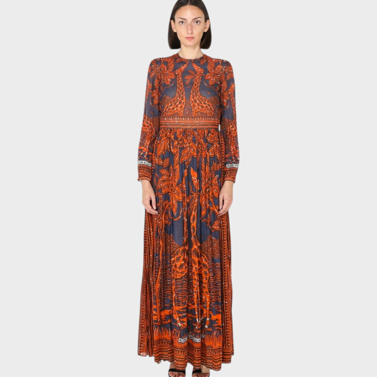 Tasoni Valentino Giraffe Bambolina dress featuring a long-sleeved, pleated maxi silhouette with orange giraffe print.