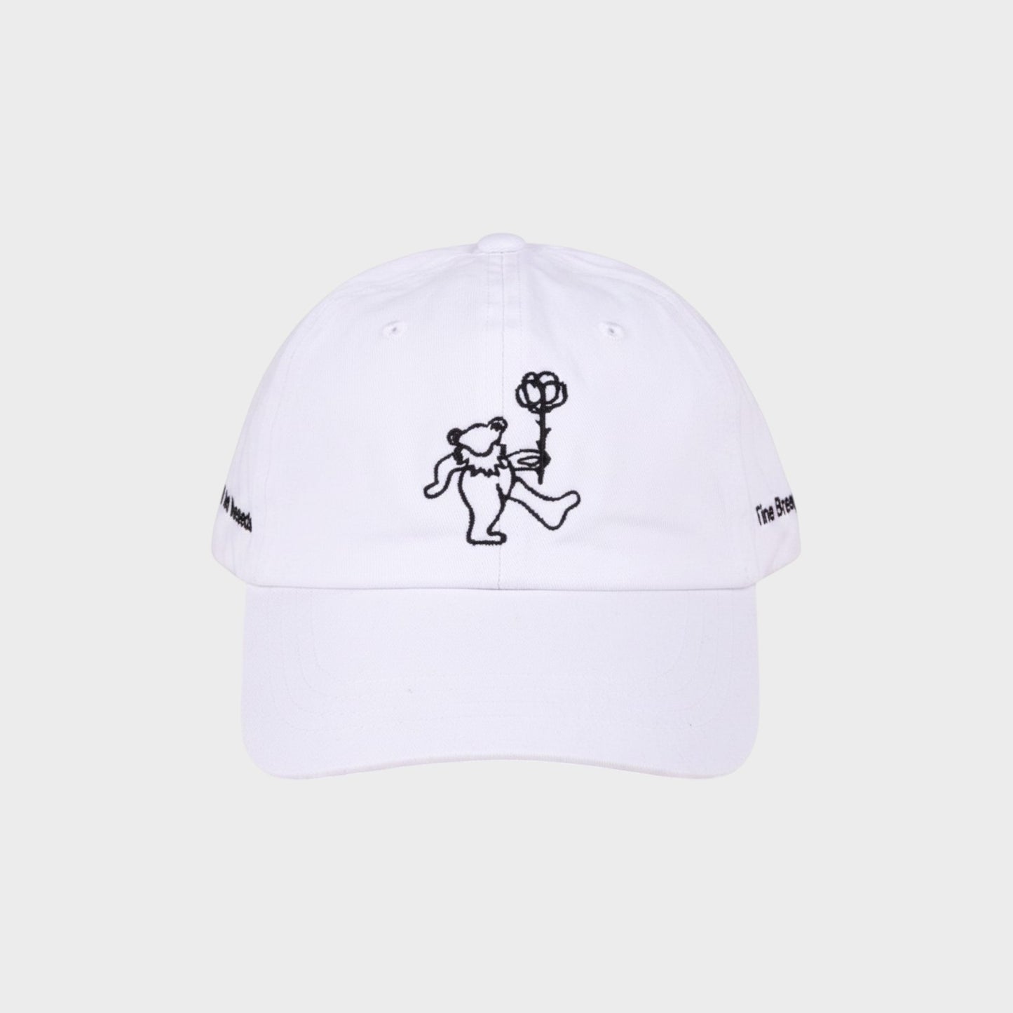 Tasoni x Tina Braegger white baseball cap with embroidered dancing bear holding a rose and text on sides.