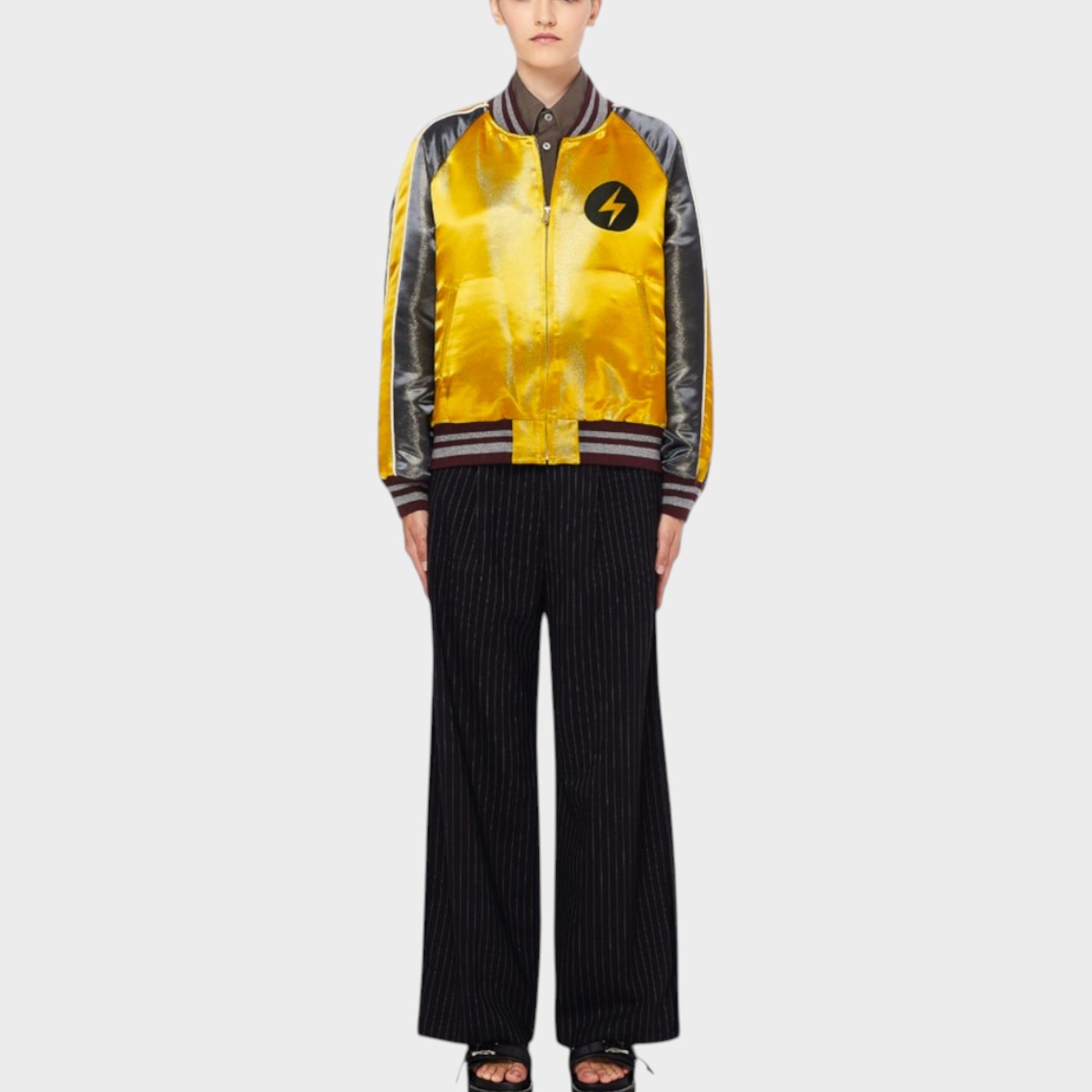 Tasoni yellow satin bomber jacket with black and grey sleeves, standing collar, and lightning bolt emblem on chest.