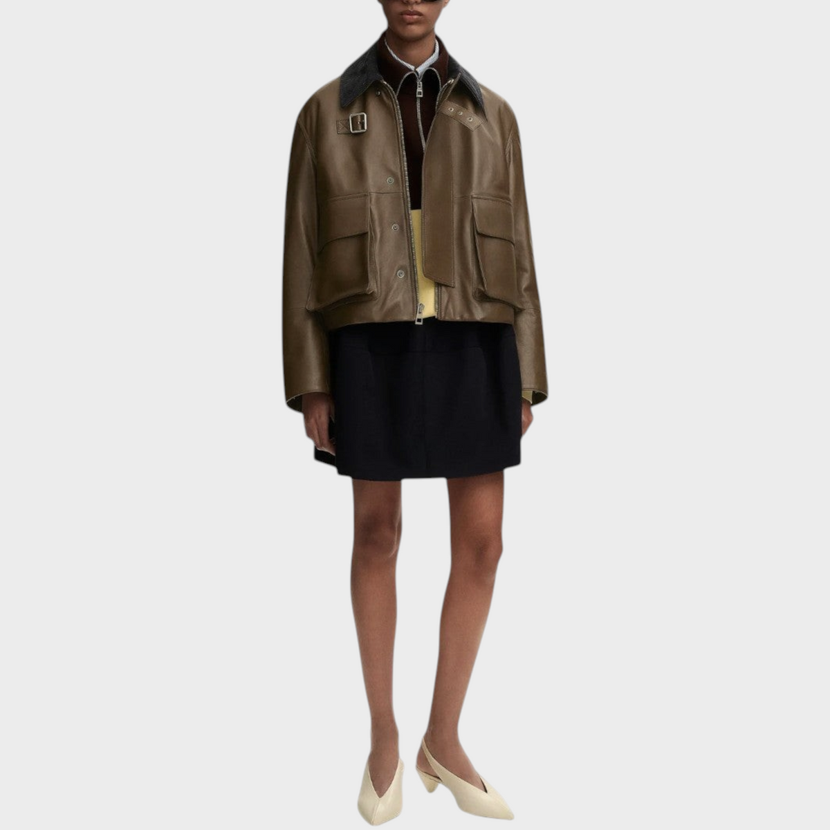 Tasoni model wearing a khaki Loewe nappa leather short parka with a stand collar and zip closure.